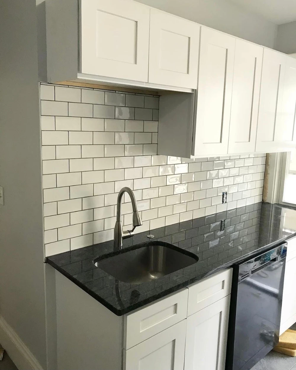 White shaker kitchen with subway tile and black granite