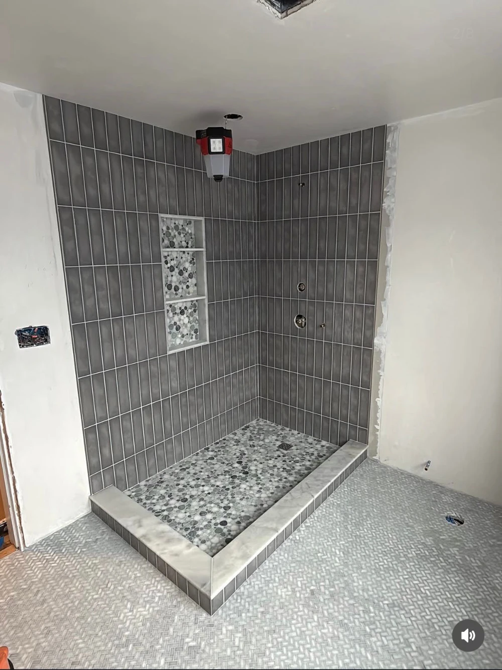 Gray vertical tile shower with pebble floor base